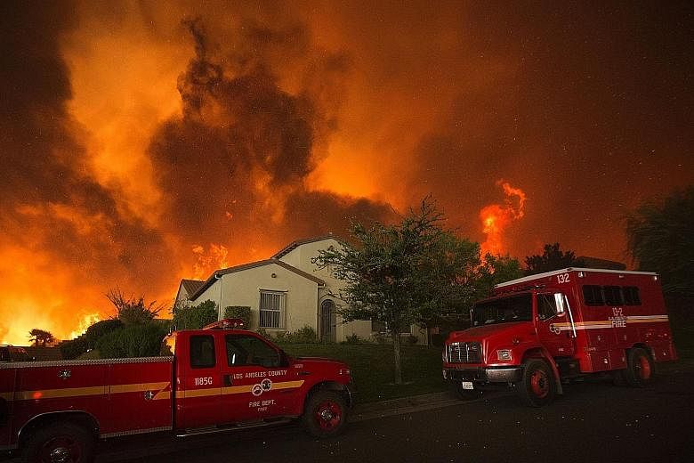 Flames and smoke from the fire looming over a house near Santa Clarita, California, on Saturday. The blaze had blackened some 8,094ha by last Saturday night.