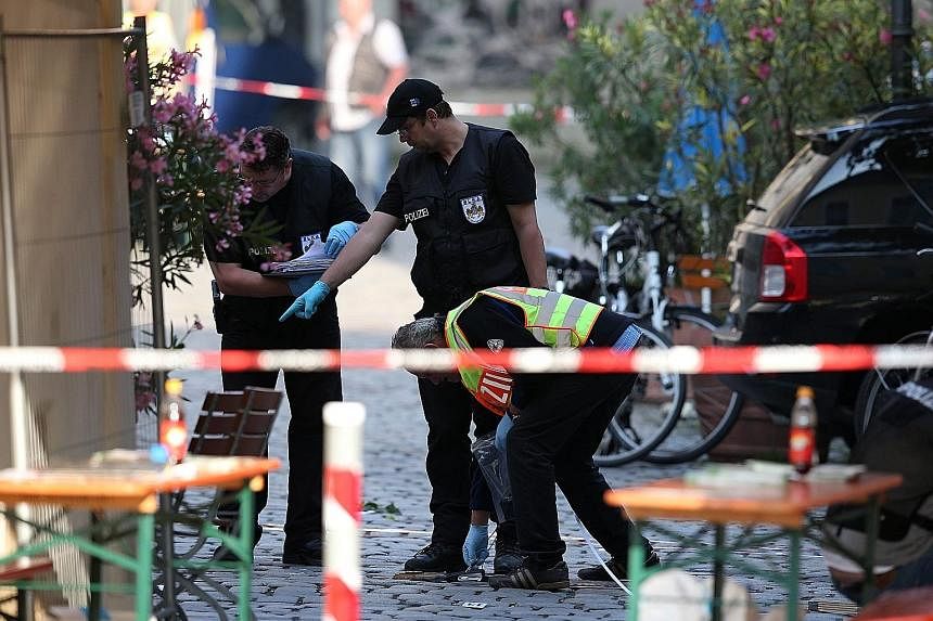 Police officers at the scene of Sunday night's suicide bombing in Ansbach, Germany, yesterday. The attacker wounded 15 people when he set off the bomb in his rucksack outside a music festival, killing himself.