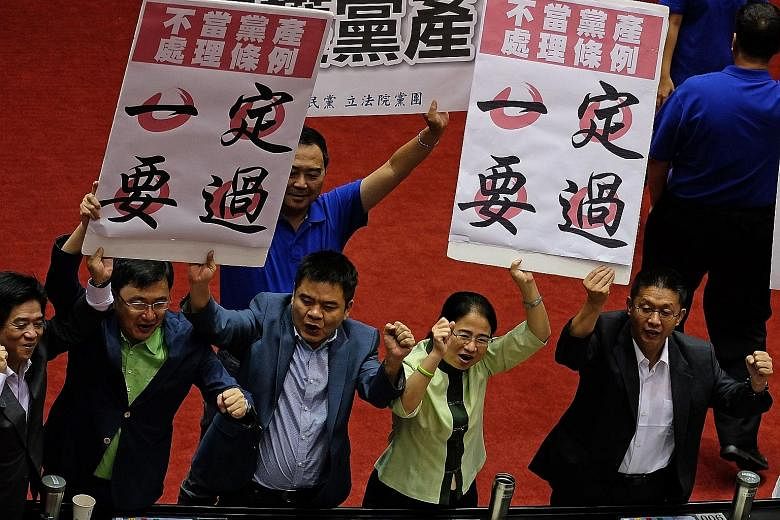 Legislators from Taiwan's ruling DPP holding placards reading "Ill-gotten party assets Bill must pass". Taiwan is set to launch an investigation into the assets of the island's political parties, a move that the opposition KMT criticised. Only the KM