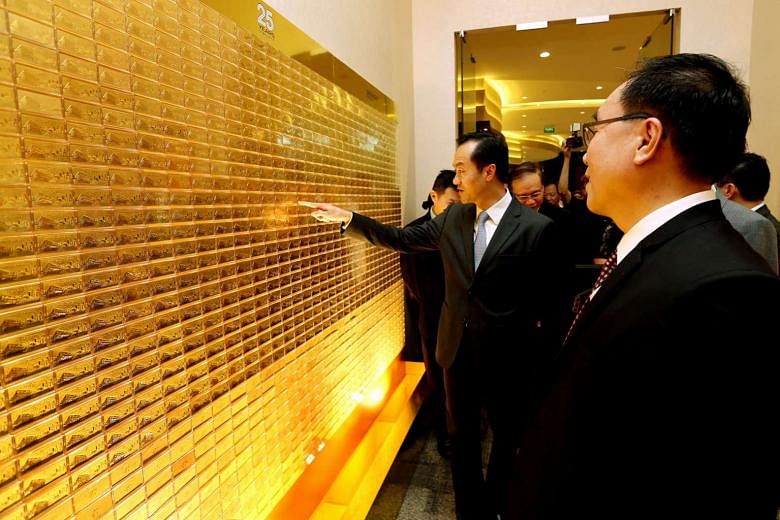 Dr Koh (centre) in front of a wall made with 9,999 pieces of 999 pure gold bars in Soo Kee Group's new corporate headquarters in Changi Business Park. 