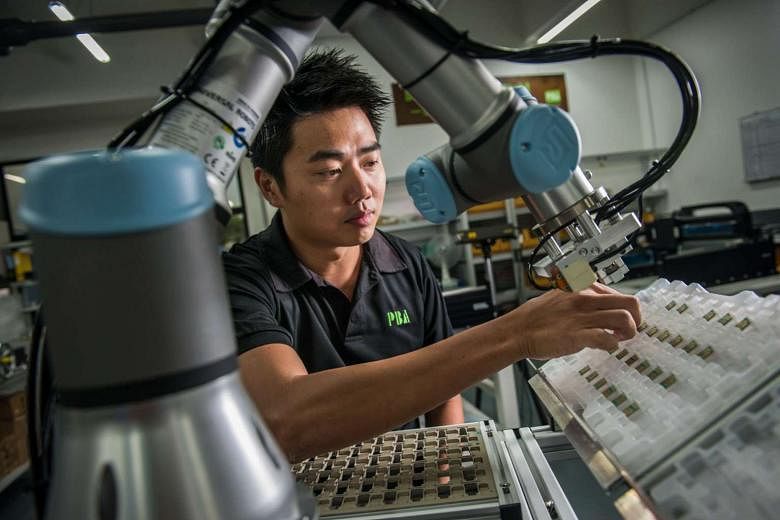 Mr Yap arranging chips on a collaborative robot pick- and-place robotic cell. His company is now moving into robotics as factories become more "humanless".