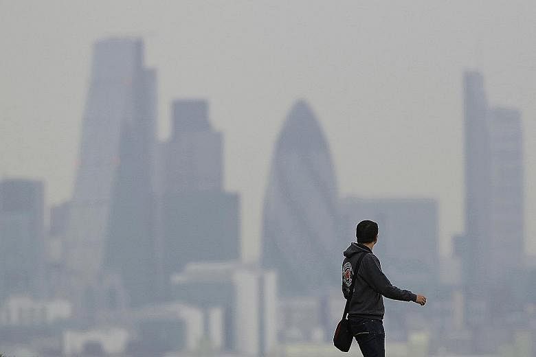 A man walks through Greenwich Park as haze sits over the London skyline in 2014.