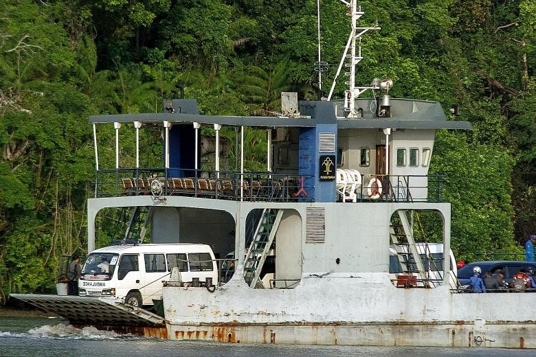 Above: A ferry with ambulances carrying coffins on board, on its way to the prison island yesterday. Right: Indonesian police officers standing guard at the gate to the port of the Nusakambangan prison island yesterday.