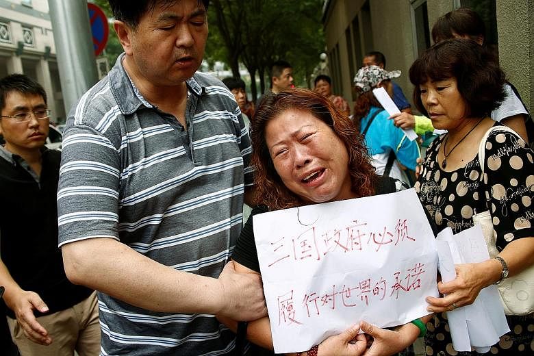 A woman holding a sign saying "The three governments have an obligation to carry out their promise to the world" at the protest outside the Chinese foreign ministry in Beijing yesterday. About 30 family members gathered to hand over a petition for th
