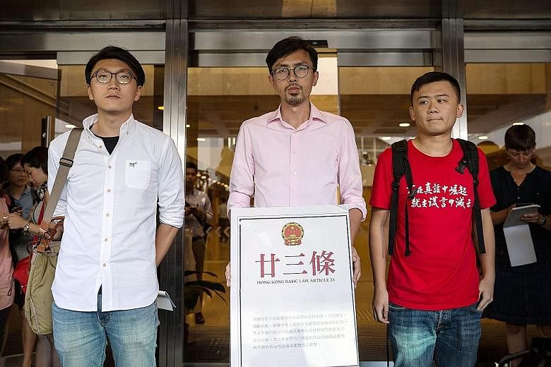 (From left) Hong Kong Indigenous' Mr Leung, League of Social Democrats chairman Avery Ng Man Yuen and League of Social Democrats' Mr Derek Chan Tak Cheung with Article 23 of the Basic Law on Wednesday outside the High Court in their bid to get the ne