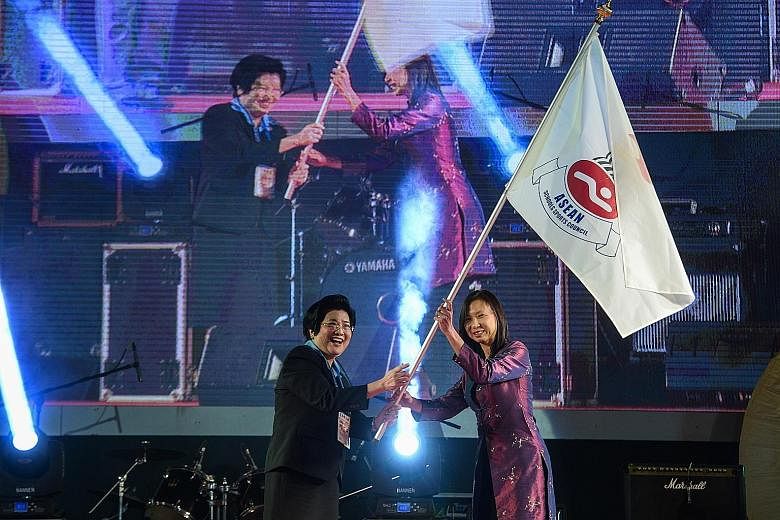 Thai associate professor Chavanee Tongroach (left), the president of the 8th Asean Schools Games organising committee, passes the Asean Schools Sports Council flag to Singapore's Liew Wei Li during the closing ceremony in Chiang Mai on Thursday. Sing