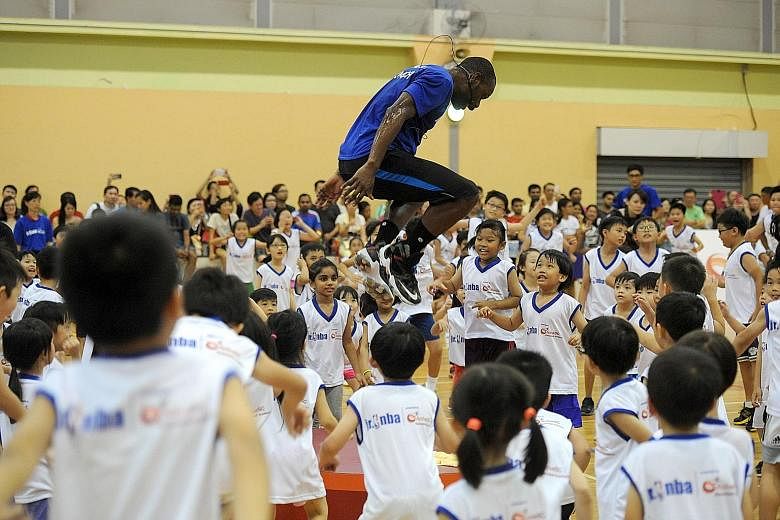 Jr NBA coach Chris Sumner (centre) jumps during a training session organised by ActiveSG Basketball Academy at the Sengkang Sports Hall. The free two-hour clinic was open to kids between five and 14 years old.