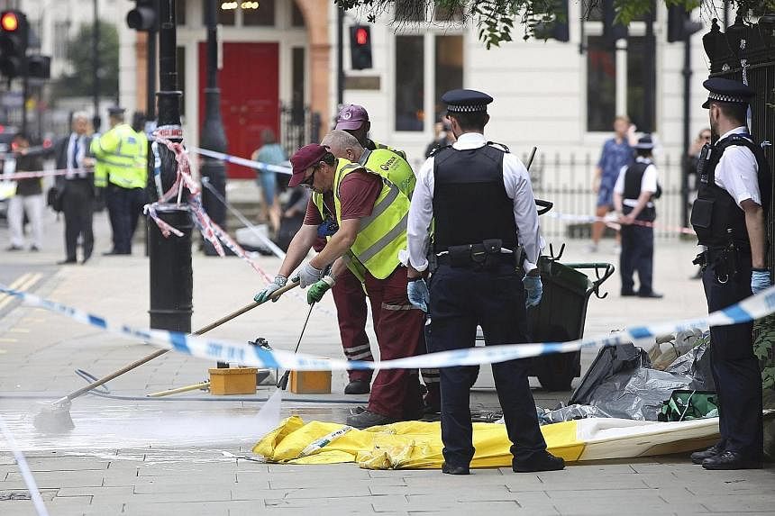 Police officers and cleaners at the scene of the knife attack in Russell Square in London yesterday. Police say that the suspect, a Norwegian man of Somali origin, seems to have chosen his victims at random.