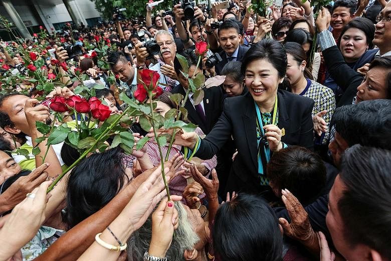 Former Thai PM Yingluck Shinawatra receiving flowers from supporters at Bangkok's supreme court yesterday. She is accused of dereliction of duty over her government's rice pledging scheme, which allowed farmers to sell their rice to the state at abou