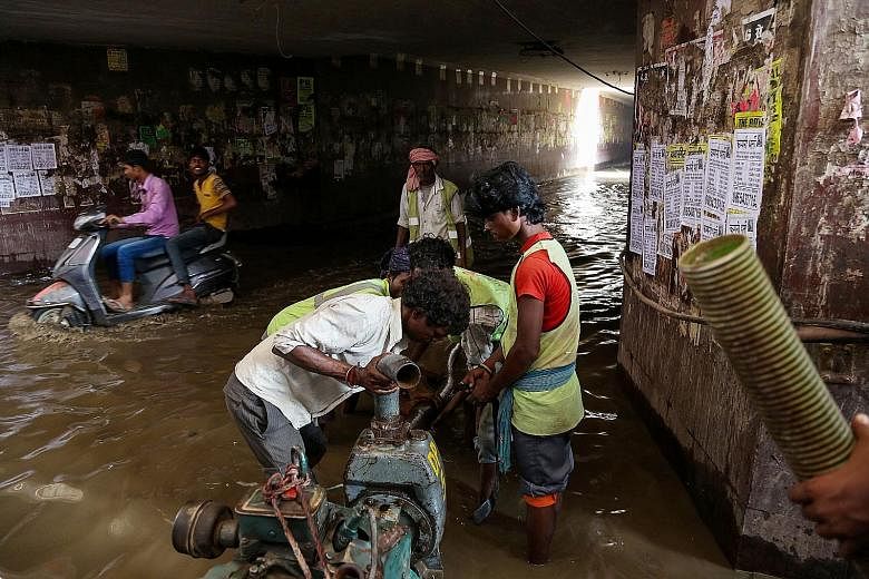 Workers using a motorised pump to clear water from a flooded subway below National Highway 8 in Gurgaon on July 30. The Haryana government has been working to improve infrastructure but it cannot keep pace with the growth of the city, which has a pop