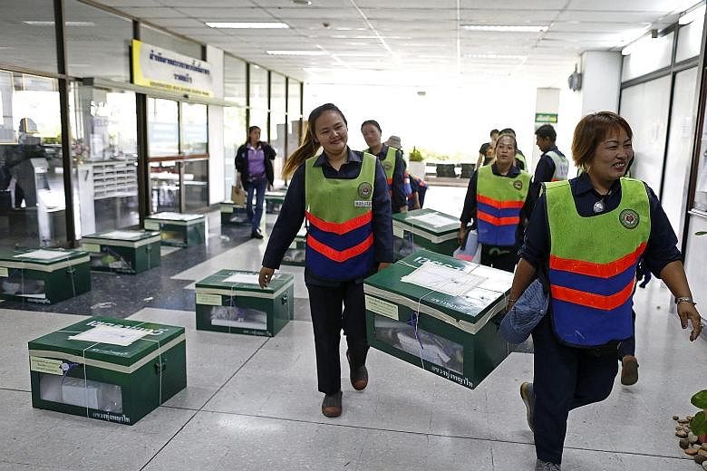 Thai workers in Bangkok carrying ballot boxes in preparation for today's vote on a draft Constitution. Several embassies, including Singapore's, have urged their nationals to take precautions during the referendum.