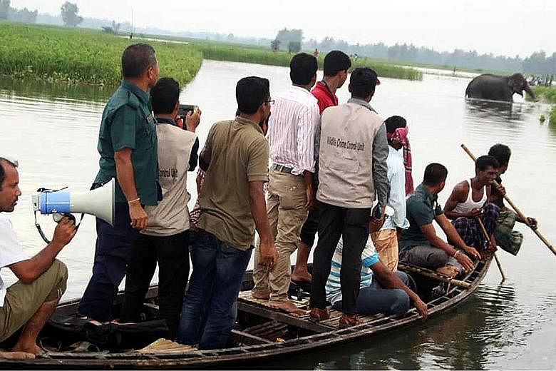 Bangladeshi wildlife officials in Jamalpur district observing the elephant, which has been avoiding dry ground because of large crowds following it.