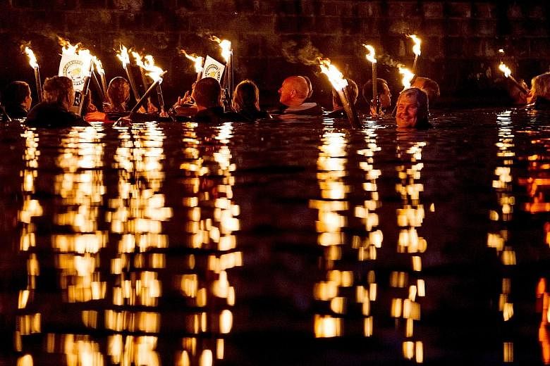 Torch swimmers forming an almost surreal tableau in Maschsee Lake in Hannover, Germany, on Saturday. About 130 swimmers plunged into the traditional torchlight swim that is an integral part of the annual lakeside festival.