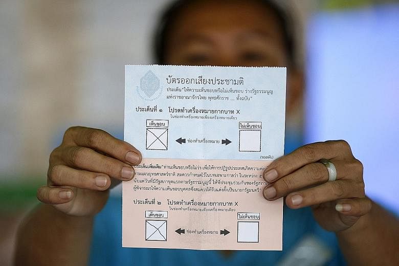 An election official shows a ballot paper in favour of Thailand's new draft charter. When adopted, this will be Thailand's 20th Constitution, and it will be harder to amend than the 2007 charter.