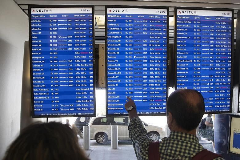 Passengers checking monitors displaying Delta Airlines flight departure schedules at LaGuardia Airport in New York on Monday. Monday morning is one of the busiest times for both airlines and travellers as business travellers begin their work week.