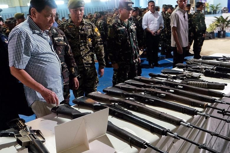 Mr Duterte inspecting confiscated firearms at a military camp in the southern Philippines on Tuesday. The President, who has been touring army camps since taking office five weeks ago, said he planned to recruit 20,000 more soldiers to help protect t