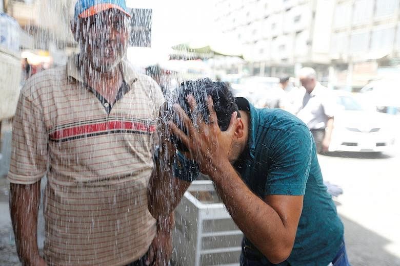 A man cooling off from the scorching summer heat in Baghdad, where the temperature measured at its international airport has reached 42 deg C or higher nearly every day since June 19.