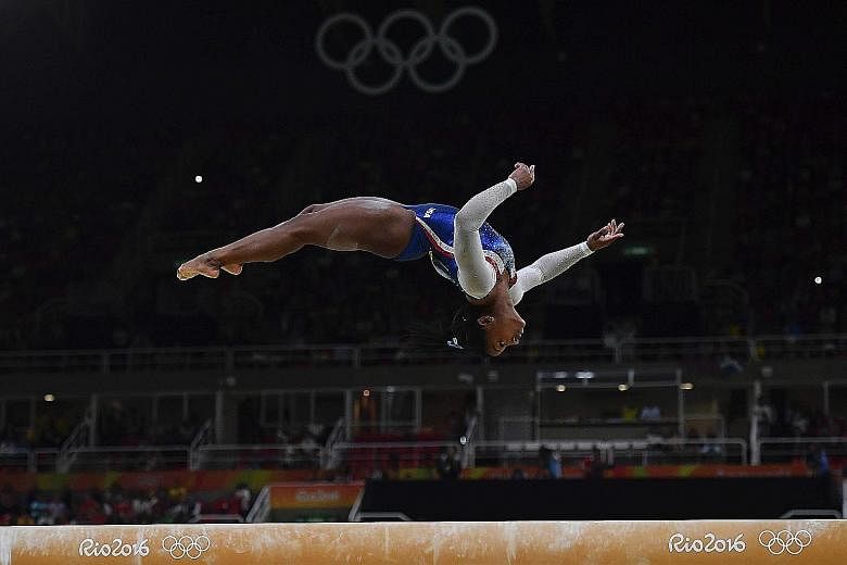 US gymnast Simone Biles executing a back flip on the beam during the all-around final. She is in the beam, vault and floor apparatus finals as well.