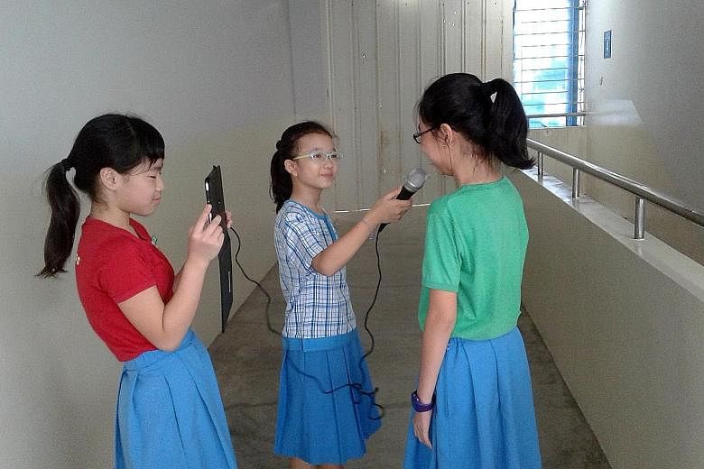 Two Jiemin Primary pupils, armed with a microphone and an iPad, interviewing a schoolmate.