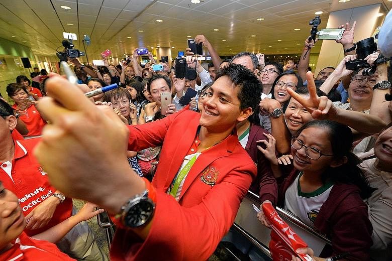 Schooling taking a photo with a crowd of supporters yesterday at Changi Airport's Terminal 3, where some had been waiting since 10pm the previous night. On an emotional and event-filled day for the swimmer, it was also announced that his NS will be d