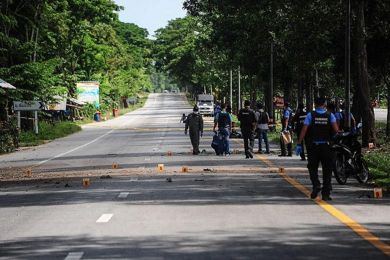 Members of a bomb squad unit inspecting the scene of a blast in the Bacho district of Thailand's southern Narathiwat province yesterday.