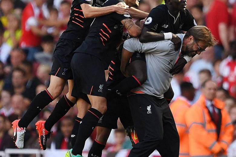 An exuberant Jurgen Klopp carrying Sadio Mane after the forward's fourth goal in their 4-3 win over Arsenal, with Adam Lallana (left) and Dejan Lovren joining in the celebrations.