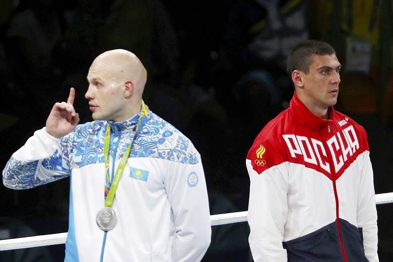 Silver medallist Vassiliy Levit of Kazakhstan gesturing for the crowd to remain silent while Russia's national anthem played for Evgeny Tishchenko, winner of the boxing heavyweight gold on a contentious decision. 
