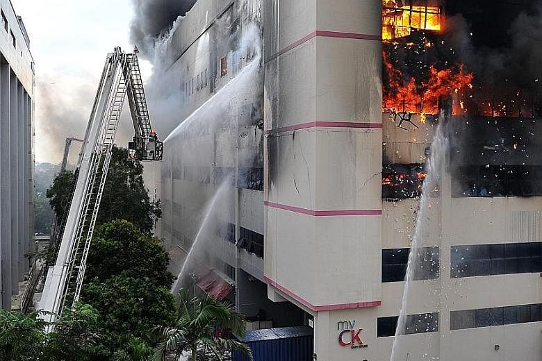 Firefighters using water jets to fight the raging flames from the outside of CK Building. The fire was brought under control after about five hours, but it had yet to be put out at press time. A column of smoke rising from CK Building in Tampines Str