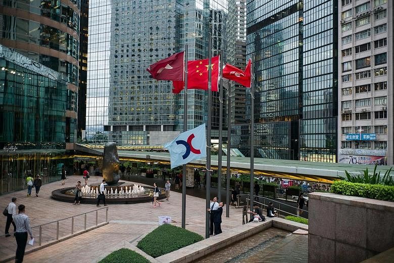 Staff of Hong Kong Exchanges and Clearing Limited lowering its flag in Hong Kong. China's central government has approved plans to link trading between the Shenzhen stock exchange and the Hong Kong market, paving the way for a long-awaited reform.