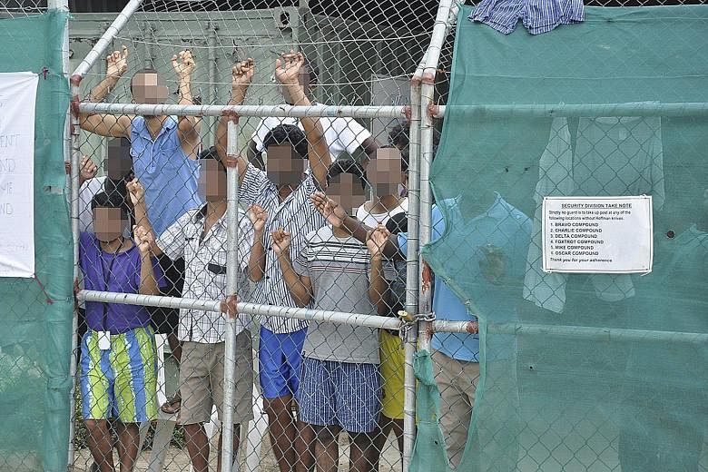 A 2014 file picture showing asylum-seekers behind a fence at the Manus Island detention centre in Papua New Guinea. The camp was in the spotlight this week after Australian media published graphic images of two Afghan men there who had allegedly been