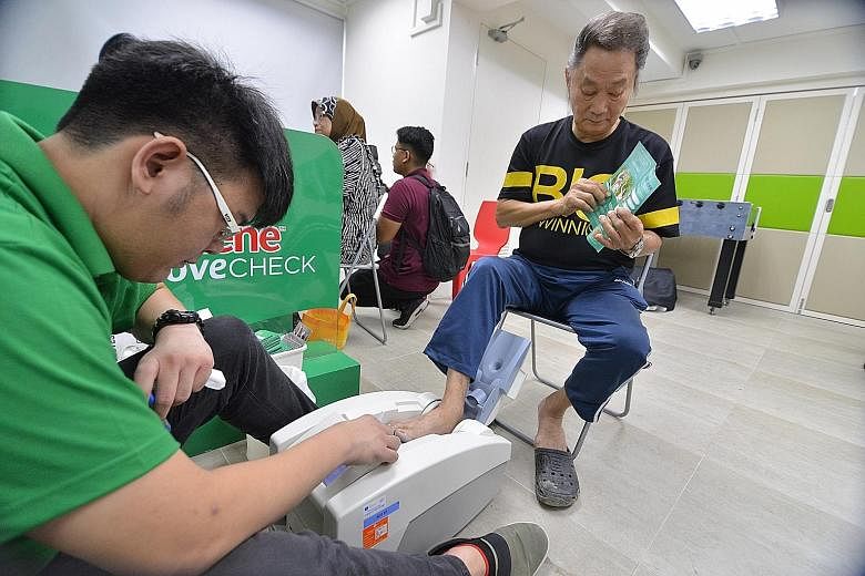 Mr Tan See Ching, 69, undergoing a scan to check his bone density and strength yesterday morning at the Lions Befrienders Bendemeer Senior Activity Centre. He is one of the 60 underprivileged seniors from the centre who were given the scan during a c