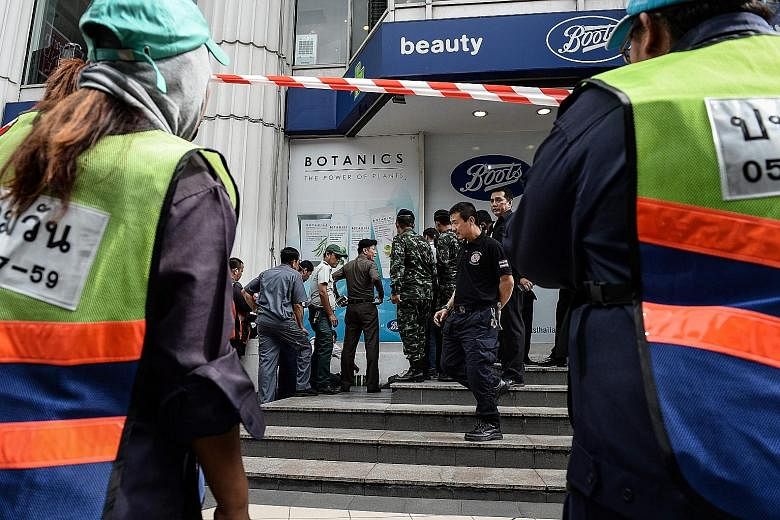 Bystanders watch as police dispose of a suspicious-looking bag in the Ratchaprasong district in Bangkok yesterday. The area is popular with tourists. The incident turned out to be a bomb scare.