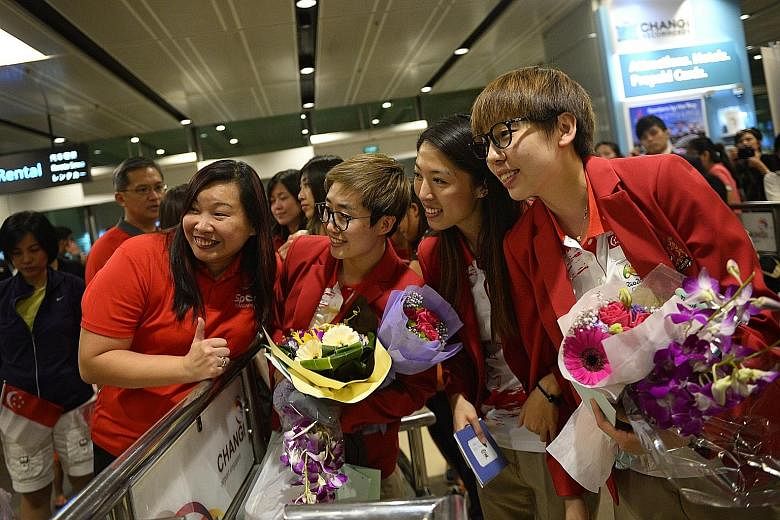 Singapore paddlers (from right) Zhou Yihan, Yu Mengyu and Feng Tianwei posing for photos with their fans upon arrival at Changi Airport yesterday. Despite not winning any Olympic medals for the first time since 2004, the table tennis players were che