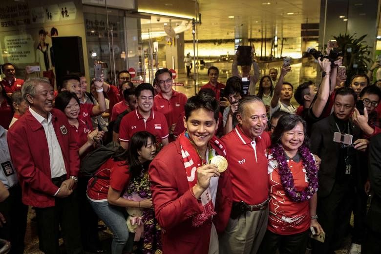 Joseph Schooling posing for photographers with his parents in Changi Airport on Monday. Joseph's backstory telegraphed the perception of the Schoolings as the perfect Singapore family - one that succeeded because they measured self-worth and achievement b