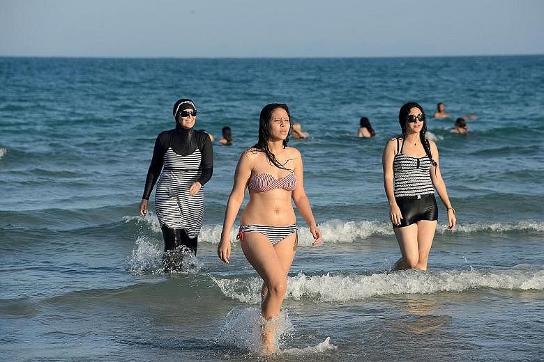 Women at Ghar El Melh beach in Tunisia, one in a burkini (left). The decision by France to ban the full-body swimming garment was decried as intolerant and counter-productive.