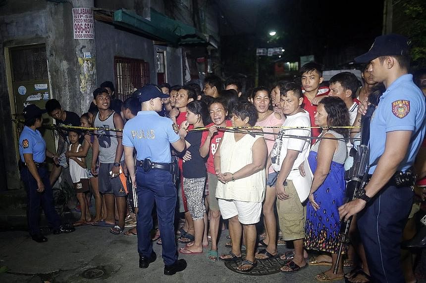 People standing behind a police line at the scene of a police operation against illegal drugs that resulted in the killing of an alleged drug dealer in Manila last Friday.