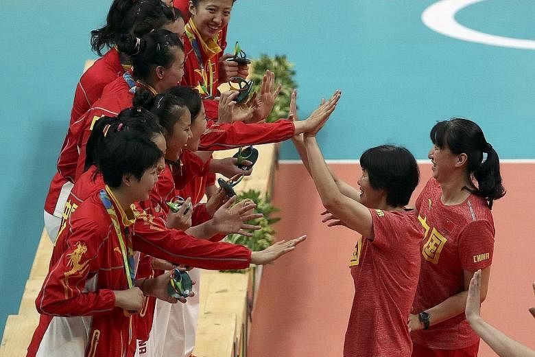 China's gold-winning volleyballers celebrating their triumph with coach Lang Ping and her assistant Lai Yawen (right). The volleyball players were one of a few bright spots of a Chinese Olympic contingent that won their fewest gold medals since the A