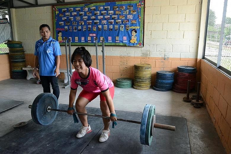 Coach Wandee Kameaim, the 58kg bronze medallist in Athens, looks on as her charge Supatcha Hadsadong trains in Suksa Songkro school's gym. Weightlifting is a way out of poverty for some Thai children.