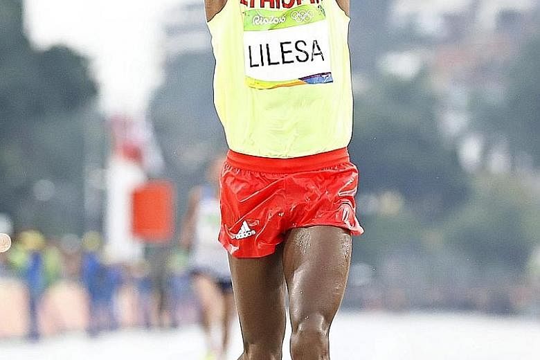 Feyisa Lilesa, 26, holding his arms in an "X" sign as he crosses the finish line to take second place in the men's marathon at the Rio Games. His gesture is a sign of protest against the Ethiopian government.