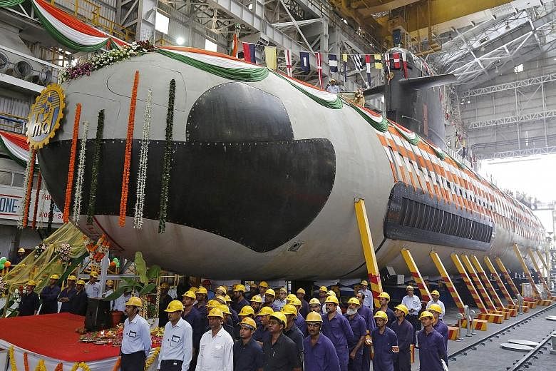 Employees standing in front of the Indian Navy's first Scorpene submarine before it was undocked from Mazagon Docks in Mumbai last year. Variants of the Scorpene-class DCNS submarine are used by Malaysia and Chile. Brazil is also due to deploy the ve