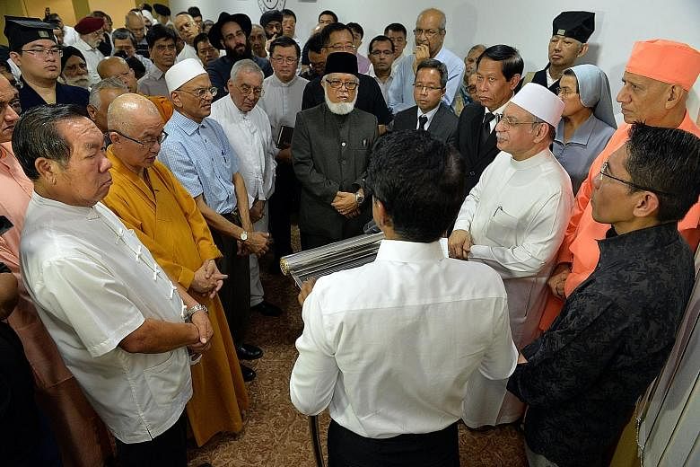 Senior Minister of State for Defence and Foreign Affairs Maliki Osman (at right in dark shirt) and leaders from the 10 faiths represented in the Inter-Religious Organisation holding a memorial service for Mr Nathan at the group's Maxwell Road office 
