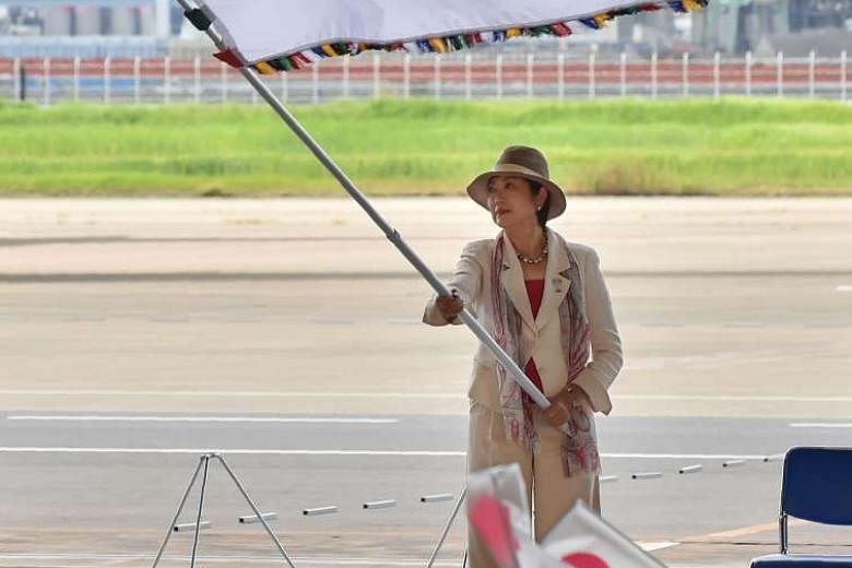 Tokyo Governor Yuriko Koike displays the Olympic flag at an arrival ceremony at Tokyo's Haneda airport yesterday, after disembarking with the flag from an All Nippon Airways plane. 