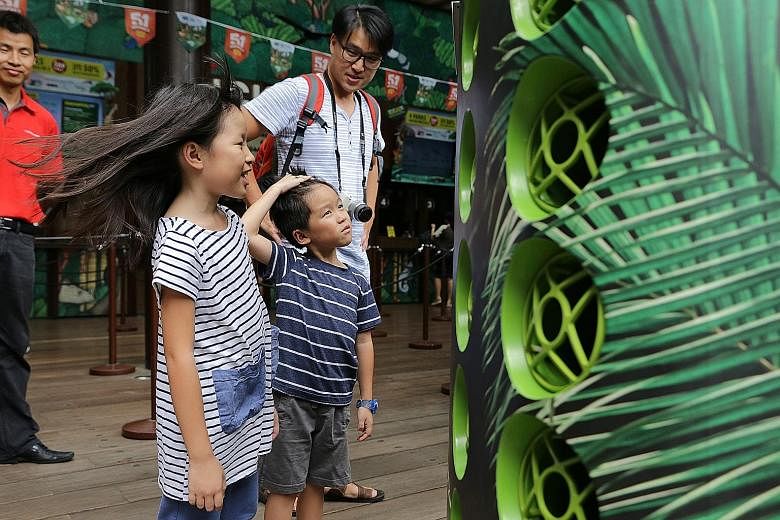 Steffi Teo, eight, and her brother, Leroy, six, enjoying the breeze from the Airbitat Smart Cooler. With them is their father, Mr Steven Teo, 38. If the trial at the zoo's ticketing area is successful, cool zones will be set up at all four wildlife p