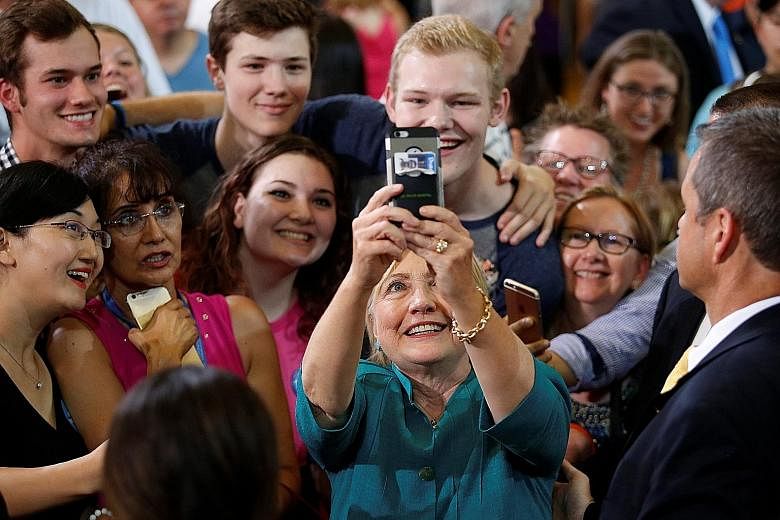 Mrs Clinton taking a wefie with supporters during a rally at Lincoln High School in Des Moines, Iowa, earlier this month. She is out to court minorities who are critical to her chances of winning in the Nov 8 election.
