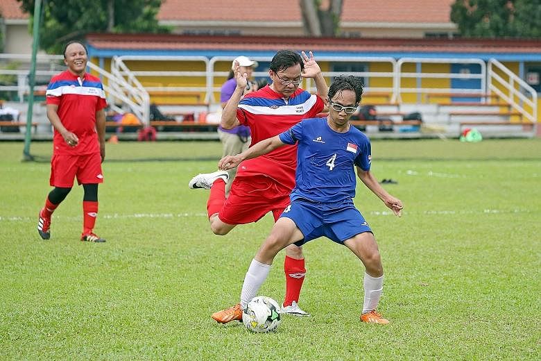 The friendly match between the Cerebral Palsy Football team and the Parliament team went ahead yesterday despite hazy conditions. Mr Shafiq Ariff (in blue), 23, is seen shielding the ball from MP Chong Kee Hiong (Bishan-Toa Payoh GRC) as MP Muhamad F
