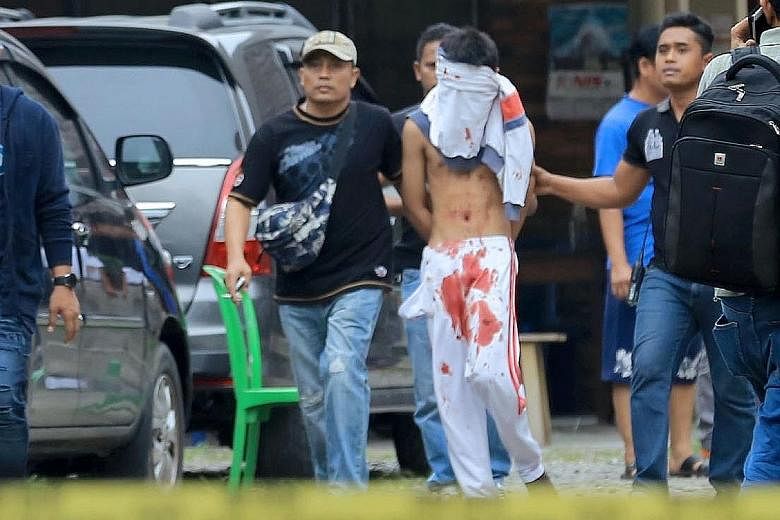 The 17-year-old attacker being escorted by plainclothes policemen in Medan yesterday.