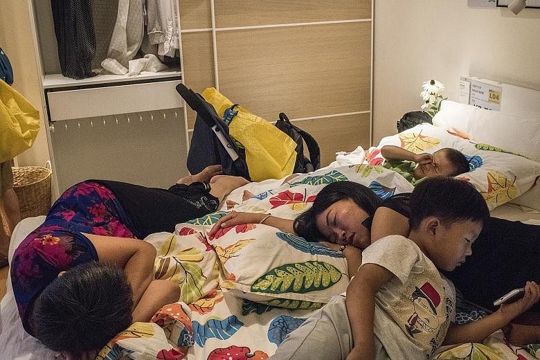 A family resting on a display bed at an Ikea store in Beijing.