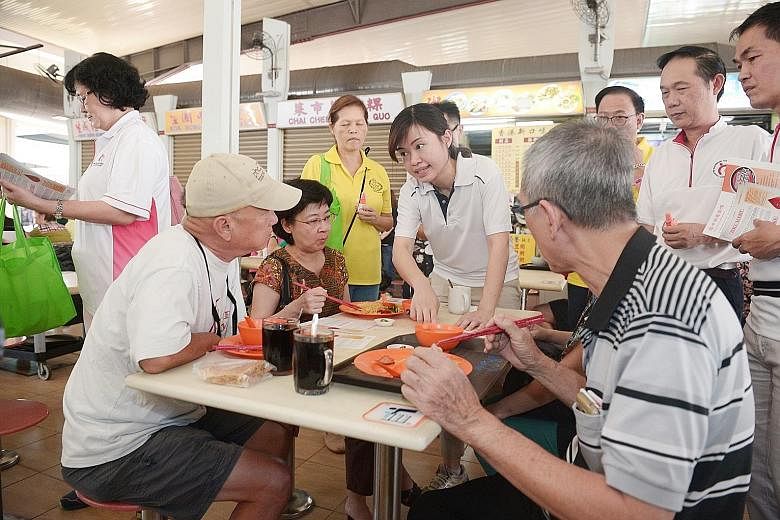 MacPherson MP Tin Pei Ling (centre) and grassroots leaders speaking to patrons at the food centre at 117, Aljunied Avenue 2 yesterday. They gave out leaflets and insect repellent, and urged people to keep their premises mosquito-free. Ms Tin said she