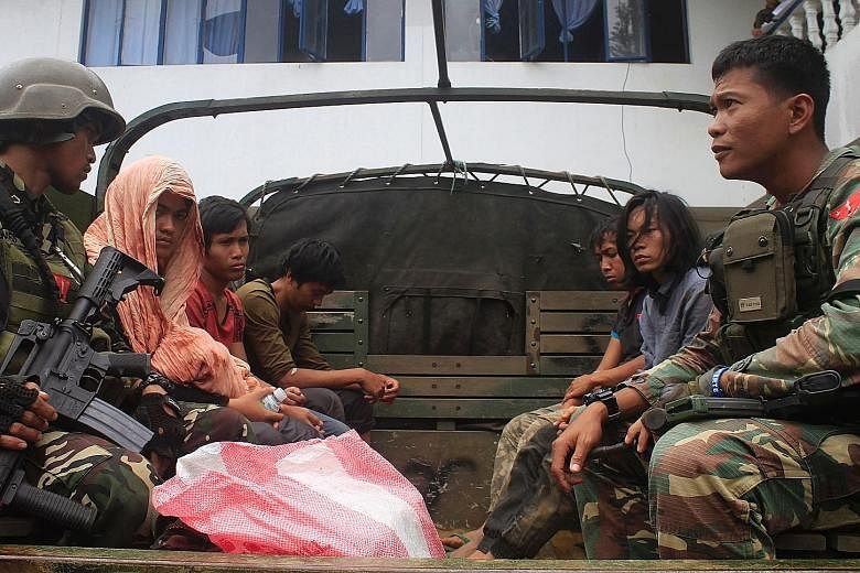 Philippine soldiers guarding members of the Maute extremist group on a military vehicle in Marawi city on the southern island of Mindanao last Tuesday, a day after they were arrested at a military checkpoint when bombs and pistols were found in the v