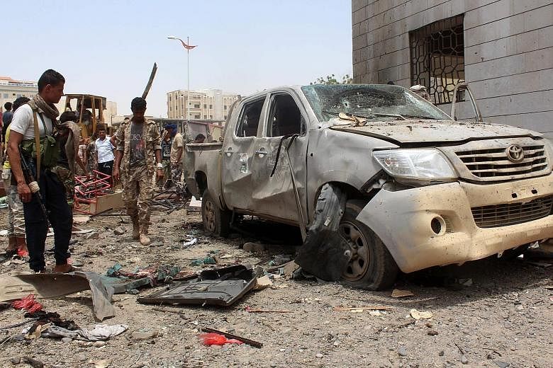 A wrecked vehicle and debris at the site of the car bombing at an army recruitment centre in Aden yesterday. ISIS has claimed the attack on its official propaganda outlet.